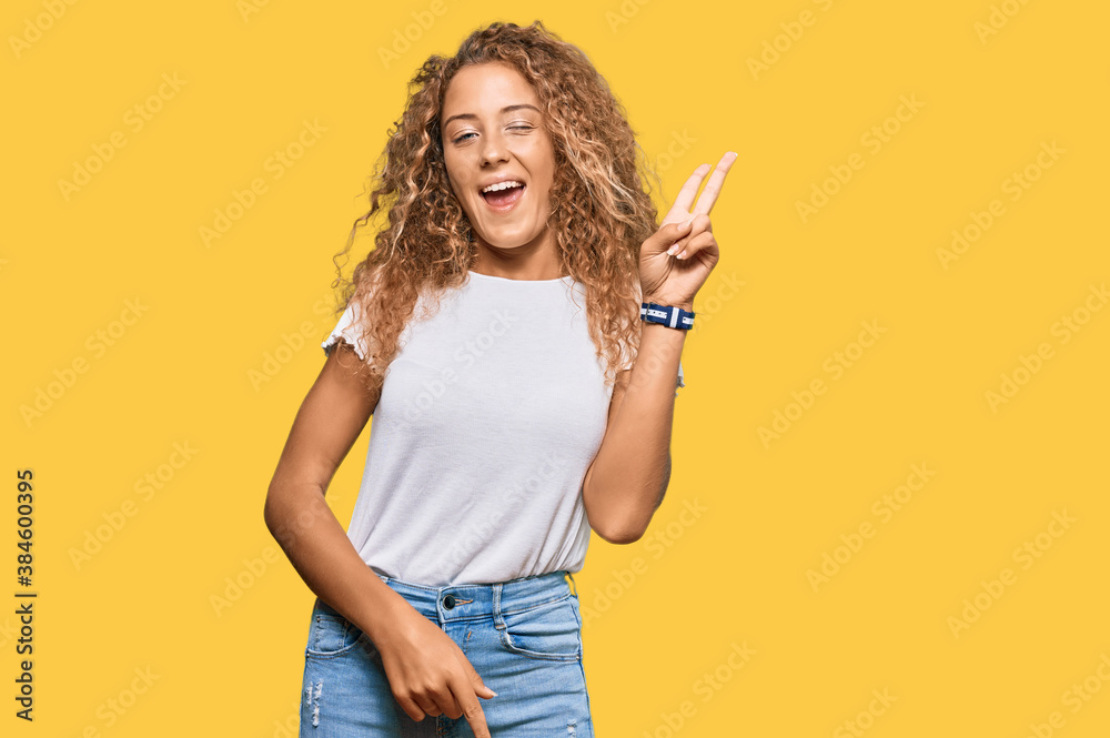 Beautiful caucasian teenager girl wearing casual white tshirt smiling with happy face winking at the camera doing victory sign with fingers. number two. Beautiful caucasian teenager girl wearing casual white tshirt smiling with happy face winking at the camera doing victory sign with fingers. number two.