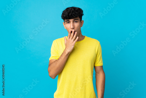 Young Argentinian man isolated on background yawning and covering wide open mouth with hand