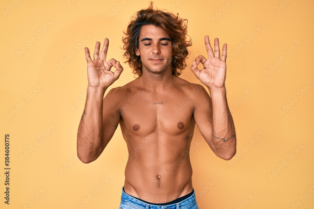 Young hispanic man standing shirtless relaxed and smiling with eyes closed doing meditation gesture with fingers. yoga concept.