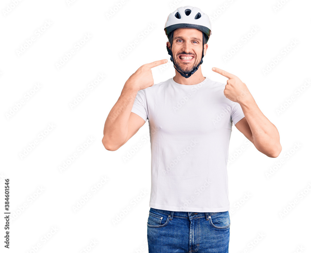 Young handsome man wearing bike helmet smiling cheerful showing and pointing with fingers teeth and mouth. dental health concept.