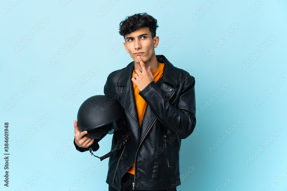 Argentinian man with a motorcycle helmet having doubts while looking up Argentinian man with a motorcycle helmet having doubts while looking up