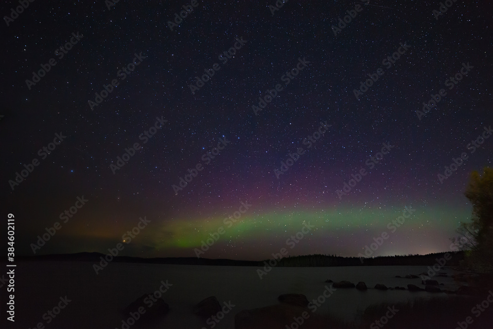 View of the aurora borealis. Polar lights in the night starry sky over the lake.