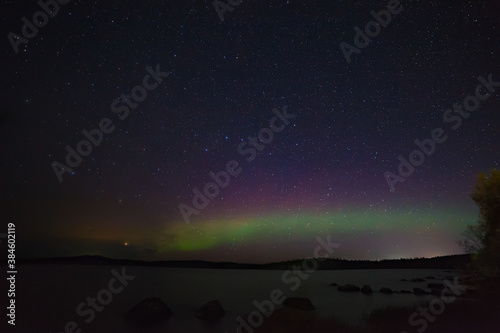 View of the aurora borealis. Polar lights in the night starry sky over the lake.