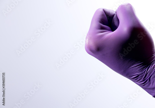 Doctor's hand with closed surgical lilac gloves, white background.