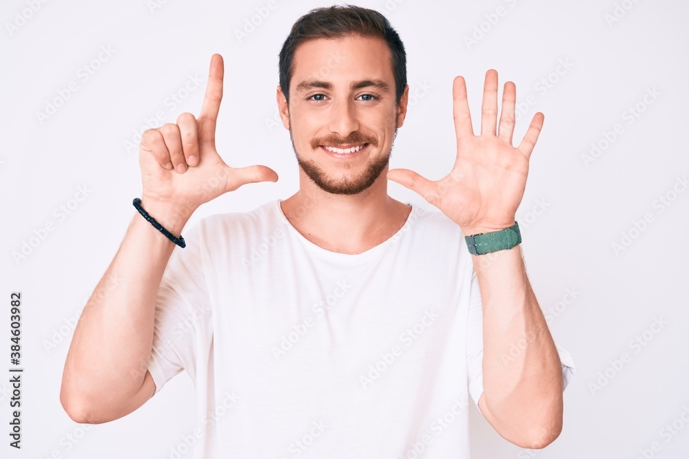 Young handsome man wearing casual white tshirt showing and pointing up with fingers number seven while smiling confident and happy. Young handsome man wearing casual white tshirt showing and pointing up with fingers number seven while smiling confident and happy.