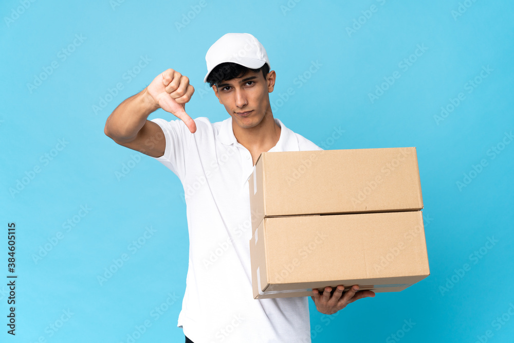 Delivery Argentinian man isolated on blue background showing thumb down with negative expression Delivery Argentinian man isolated on blue background showing thumb down with negative expression