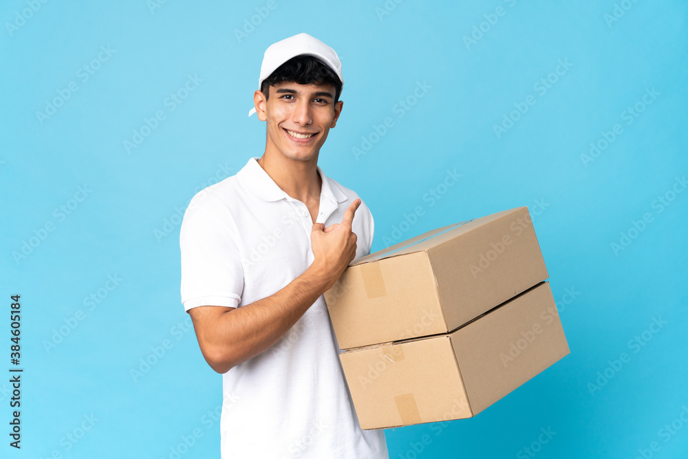 Delivery Argentinian man isolated on blue background pointing back Delivery Argentinian man isolated on blue background pointing back