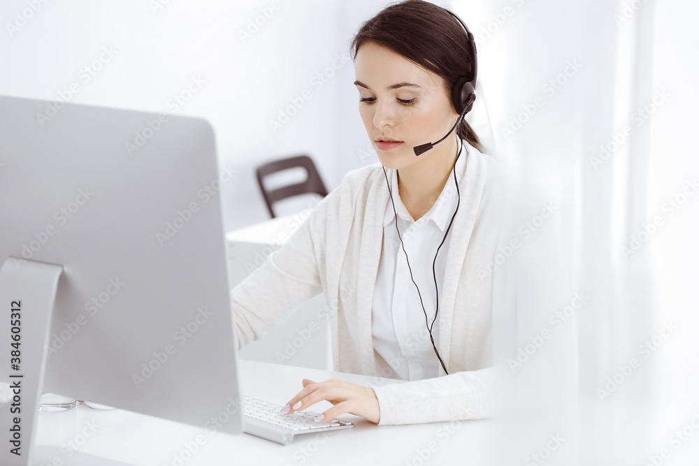 Call center. Casual dressed woman sitting in headset at customer service office. Group of operators at work. Business concept Call center. Casual dressed woman sitting in headset at customer service office. Group of operators at work. Business concept