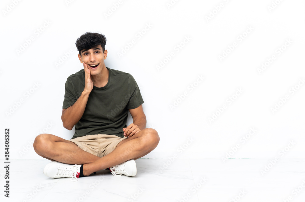 Young Argentinian man sitting on the floor with surprise and shocked facial expression Young Argentinian man sitting on the floor with surprise and shocked facial expression