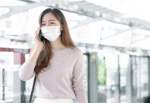 Woman wearing face mask and talking on mobile phone while standing on railway station