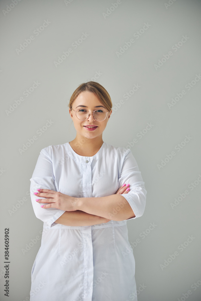 Good-looking cosmetician with folded arms standing indoors Good-looking cosmetician with folded arms standing indoors