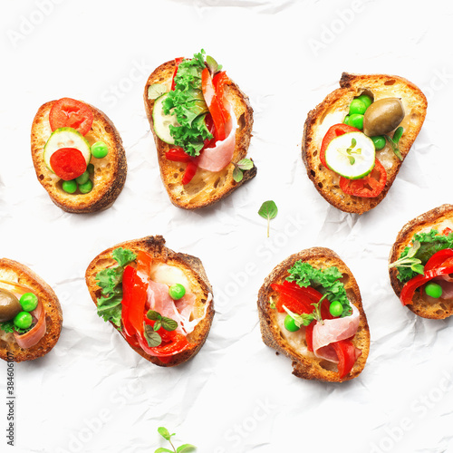 Finger food. Appetizing crostini with baked capsicum, green peas, bacon, kale and lettuce as a festive snack. Top view,