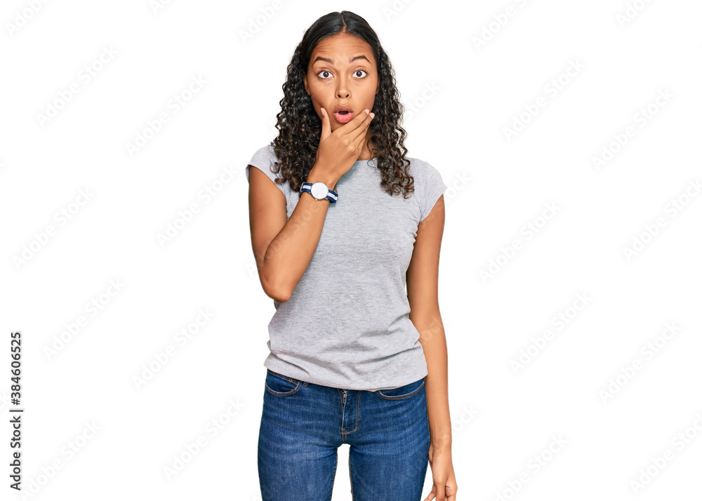 Young african american girl wearing casual clothes looking fascinated with disbelief, surprise and amazed expression with hands on chin Young african american girl wearing casual clothes looking fascinated with disbelief, surprise and amazed expression with hands on chin