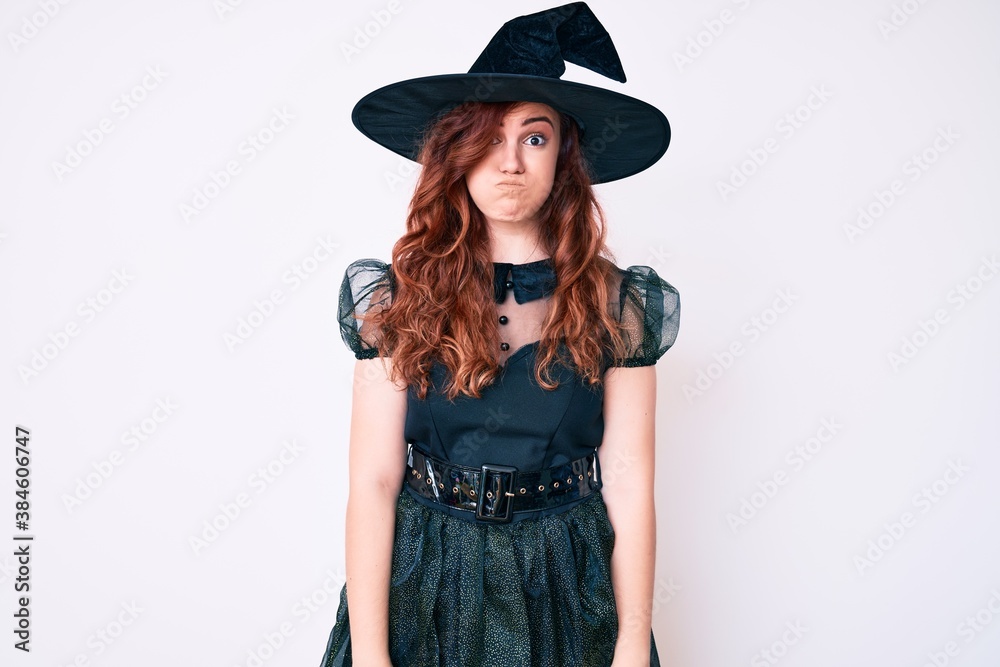 Young beautiful woman wearing witch halloween costume puffing cheeks with funny face. mouth inflated with air, crazy expression. Young beautiful woman wearing witch halloween costume puffing cheeks with funny face. mouth inflated with air, crazy expression.