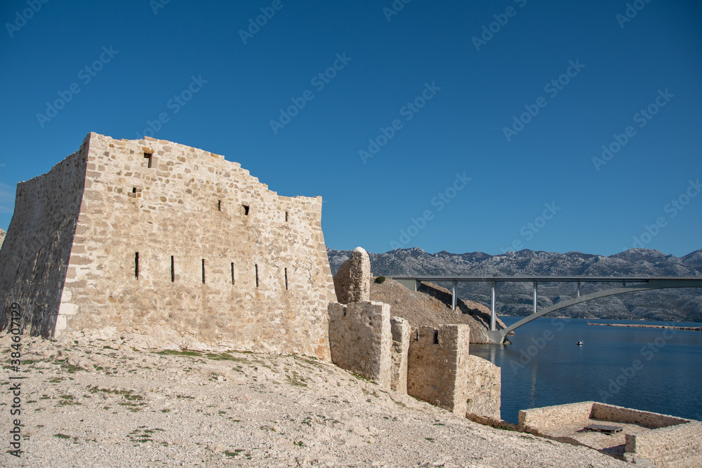 PAG ISLAND, CROATIA, 10.10.2020. Ruins of Fortica fortress and Pag bridge in distance