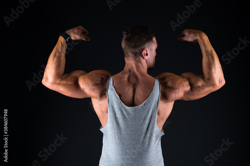 Lets get that body trained. Fit guy flex arms showing biceps triceps. Muscle power. Power and strength. Fitness and sport. Health and wellness. Bodybuilder back view black background