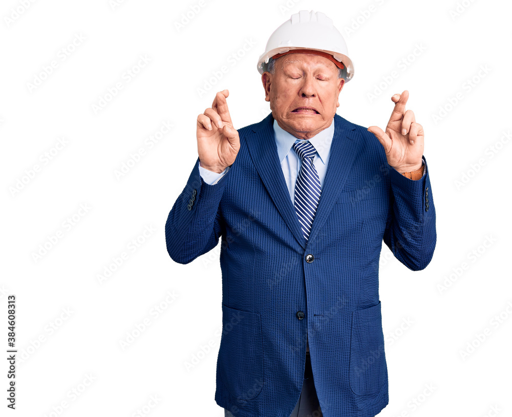 Senior handsome grey-haired man wearing suit and architect hardhat gesturing finger crossed smiling with hope and eyes closed. luck and superstitious concept. Senior handsome grey-haired man wearing suit and architect hardhat gesturing finger crossed smiling with hope and eyes closed. luck and superstitious concept.