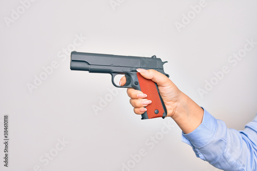Hand of caucasian young woman holding gun over isolated white background photo