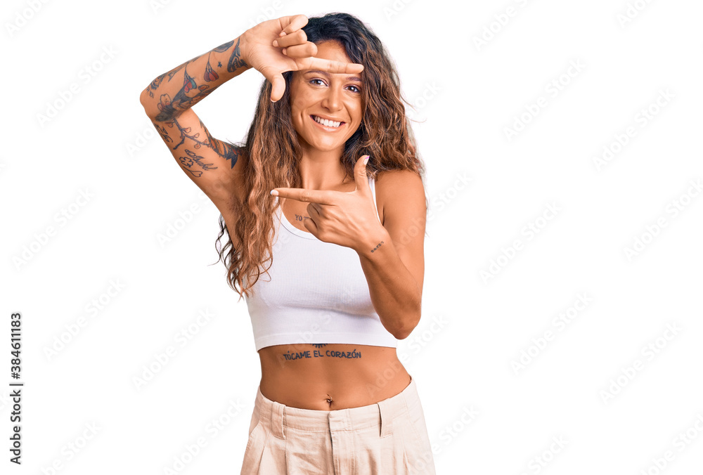 Young hispanic woman with tattoo wearing casual clothes smiling making frame with hands and fingers with happy face. creativity and photography concept. Young hispanic woman with tattoo wearing casual clothes smiling making frame with hands and fingers with happy face. creativity and photography concept.