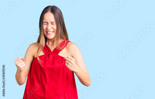 Beautiful brunette young woman wearing casual clothes very happy and excited doing winner gesture with arms raised, smiling and screaming for success. celebration concept.