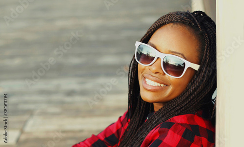 Portrait of happy young smiling african woman wearing a sunglasses in casual over city background