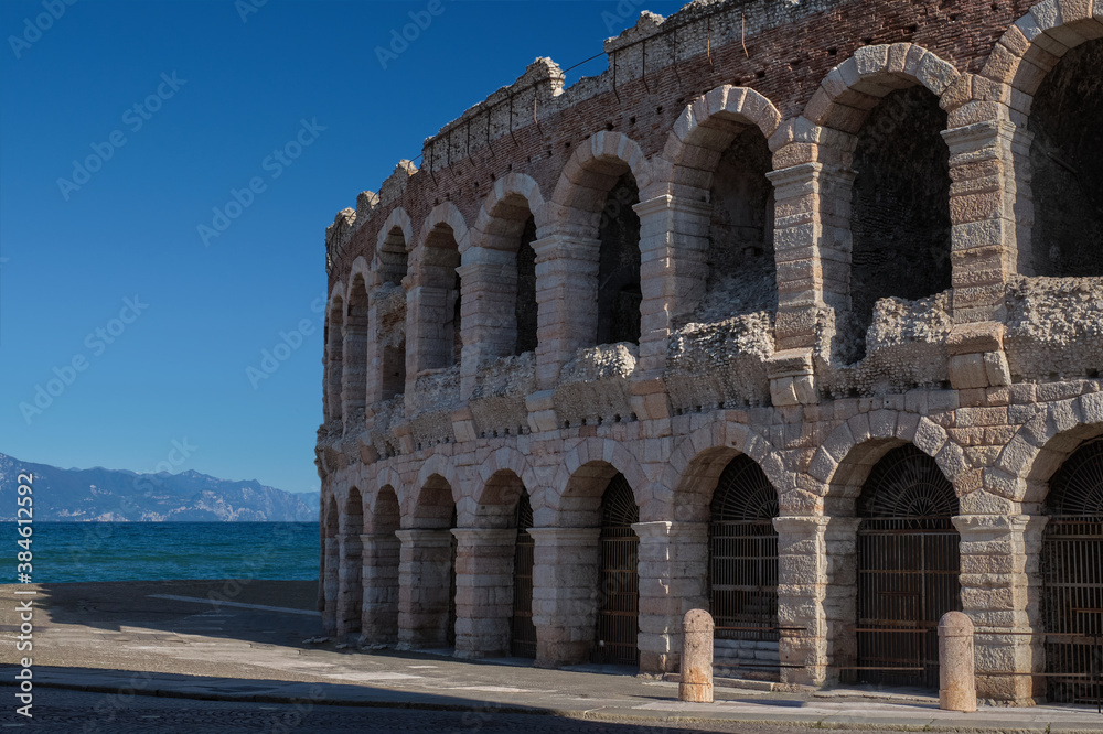 Roman amphitheater in Italy in the background water, mountains and blue sky