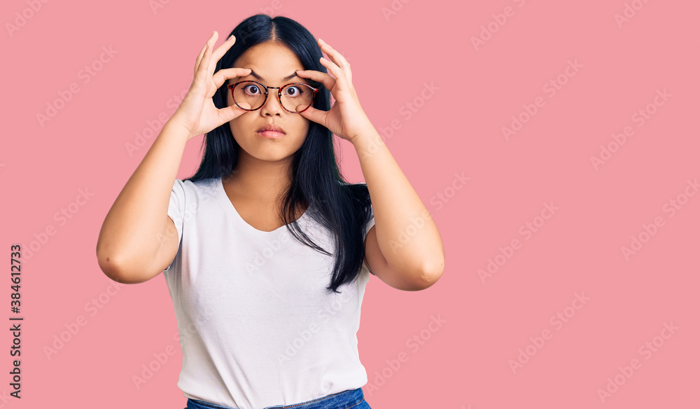 Young beautiful asian girl wearing casual clothes and glasses trying to open eyes with fingers, sleepy and tired for morning fatigue Young beautiful asian girl wearing casual clothes and glasses trying to open eyes with fingers, sleepy and tired for morning fatigue