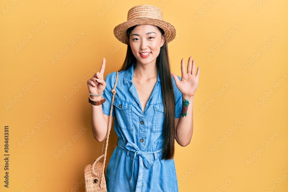 Young chinese woman wearing summer hat showing and pointing up with fingers number six while smiling confident and happy. Young chinese woman wearing summer hat showing and pointing up with fingers number six while smiling confident and happy.