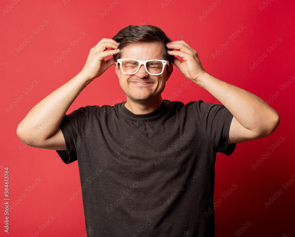 Man in glasses and shirt with headache on red background Man in glasses and shirt with headache on red background
