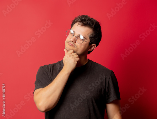 Man in glasses and shirt on red background © Masson