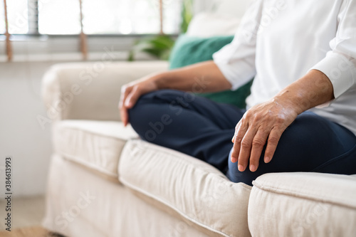 Senior old Asian woman sitting on sofa practicing yoga and meditation at home  retirement and wellbeing concept