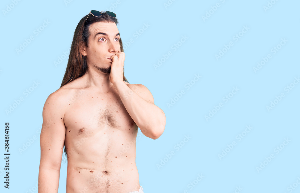 Fototapeta premium Young adult man with long hair wearing swimwear shirtless looking stressed and nervous with hands on mouth biting nails. anxiety problem.