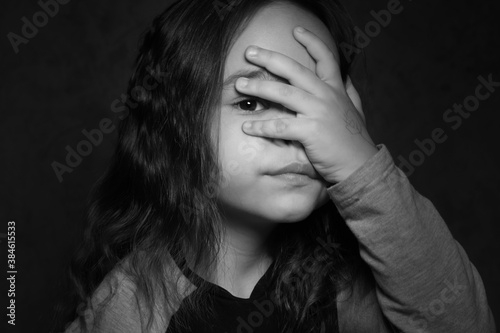 Girl looks through her fingers black and white photo