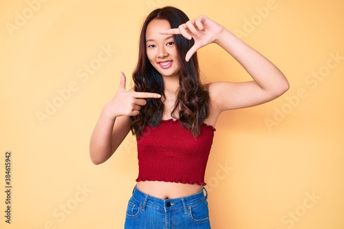 Young beautiful chinese girl wearing summer clothes smiling making frame with hands and fingers with happy face. creativity and photography concept.