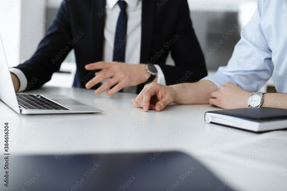 Unknown business people using laptop computer at the desk in modern office. Businessman or male entrepreneur is working with his colleague. Teamwork and partnership concept Unknown business people using laptop computer at the desk in modern office. Businessman or male entrepreneur is working with his colleague. Teamwork and partnership concept