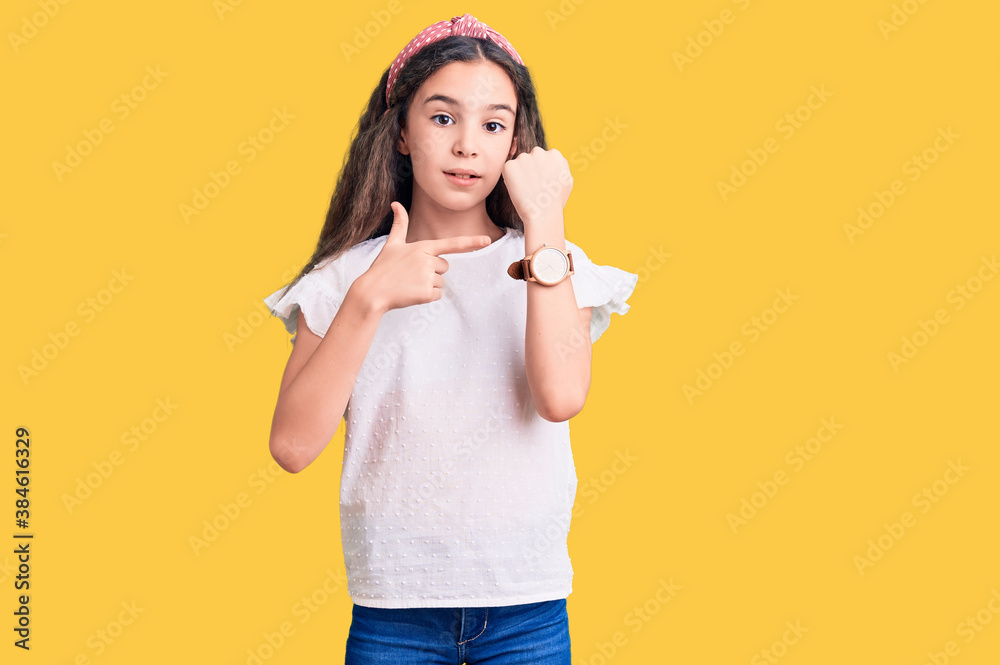 Cute hispanic child girl wearing casual white tshirt in hurry pointing to watch time, impatience, looking at the camera with relaxed expression Cute hispanic child girl wearing casual white tshirt in hurry pointing to watch time, impatience, looking at the camera with relaxed expression