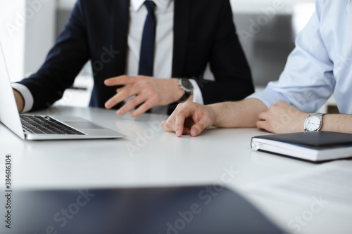 Unknown business people using laptop computer at the desk in modern office. Businessman or male entrepreneur is working with his colleague. Teamwork and partnership concept © Iryna