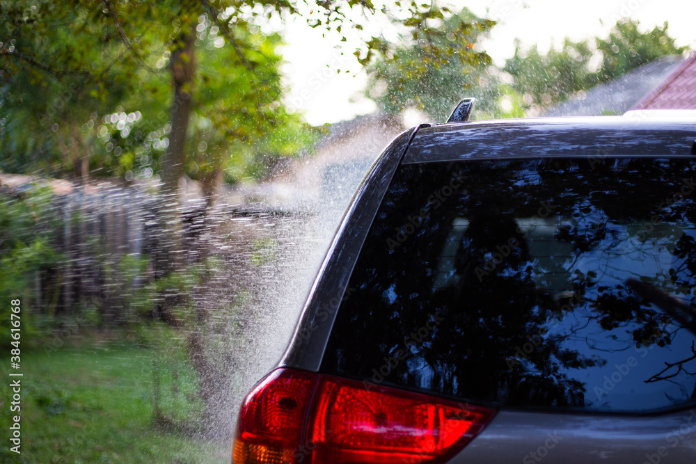 car wash in the courtyard of the house, a jet of water is sprayed on the glass.