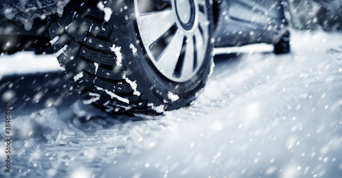 Closeup of the car tire on winter road covered with snow in snowfall © candy1812