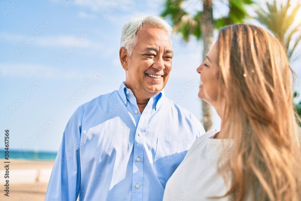 Middle age hispanic couple smiling happy hugging at the promenade.