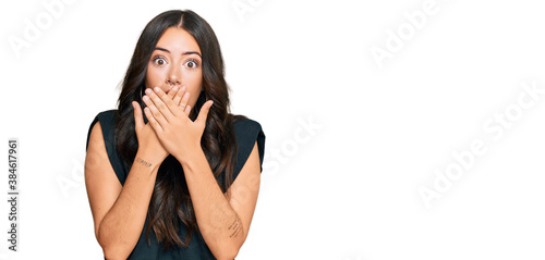 Beautiful brunette young woman wearing black shirt shocked covering mouth with hands for mistake. secret concept.