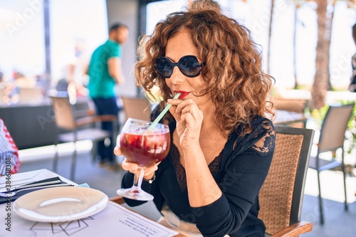 Fototapeta Middle age beautiful brunette woman wearing sunglasses
