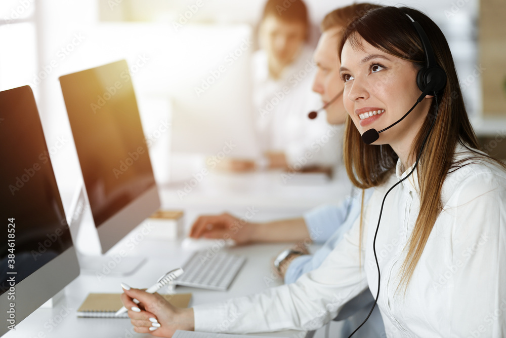 Asian woman working at customer service office. Business concept. Group of diverse operators at work in sunny call center. Asian woman working at customer service office. Business concept. Group of diverse operators at work in sunny call center.