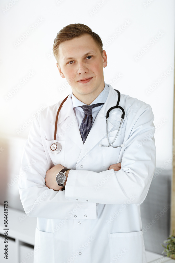 Man-doctor standing straight in sunny clinic. Medicine concept Man-doctor standing straight in sunny clinic. Medicine concept