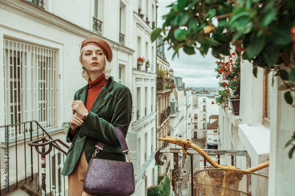 © Victoria Fox - Outdoor autumn portrait of young  fashionable woman wearing trendy brown leather beret, turtleneck, green velour blazer, holding textured purple bag, posing in street of Paris. Copy space