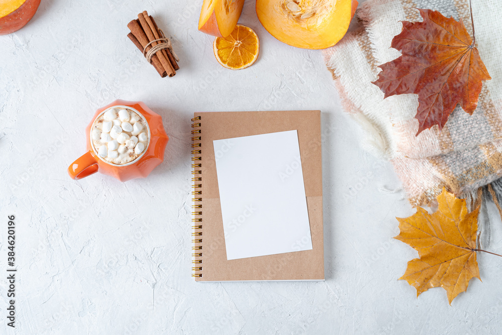 Desktop mock up planner. Top view composition with notebook, pumpkin styled cup of coffee with marshmallows and autumn themed decoration, fallen leaves on white background. Flat lay, copy space. Desktop mock up planner. Top view composition with notebook, pumpkin styled cup of coffee with marshmallows and autumn themed decoration, fallen leaves on white background. Flat lay, copy space.