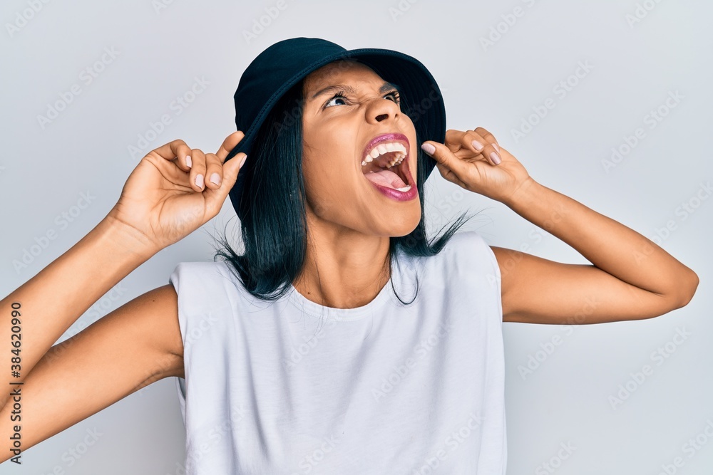 Young african american woman wearing fashion hat angry and mad screaming frustrated and furious, shouting with anger looking up. Young african american woman wearing fashion hat angry and mad screaming frustrated and furious, shouting with anger looking up.