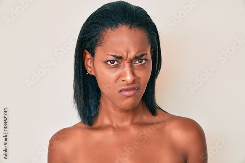Young african american woman standing topless showing skin skeptic and nervous, frowning upset because of problem. negative person.