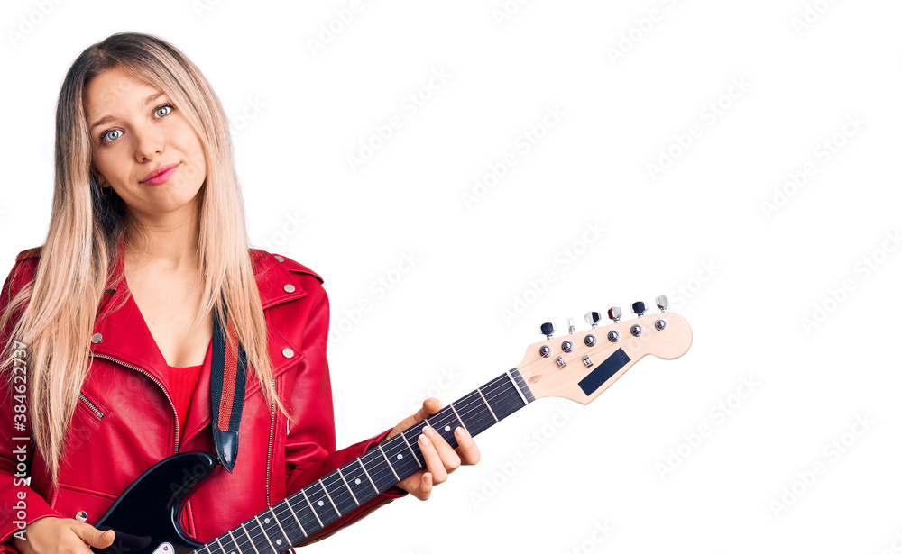Young beautiful blonde woman playing electric guitar thinking attitude and sober expression looking self confident