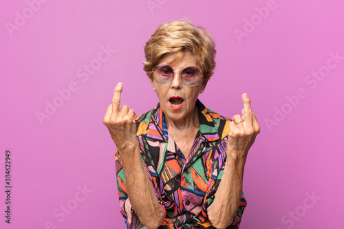 old pretty woman feeling provocative, aggressive and obscene, flipping the middle finger, with a rebellious attitude